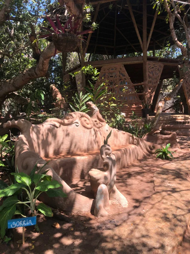Escultura de barro em forma de criatura deitada em um jardim